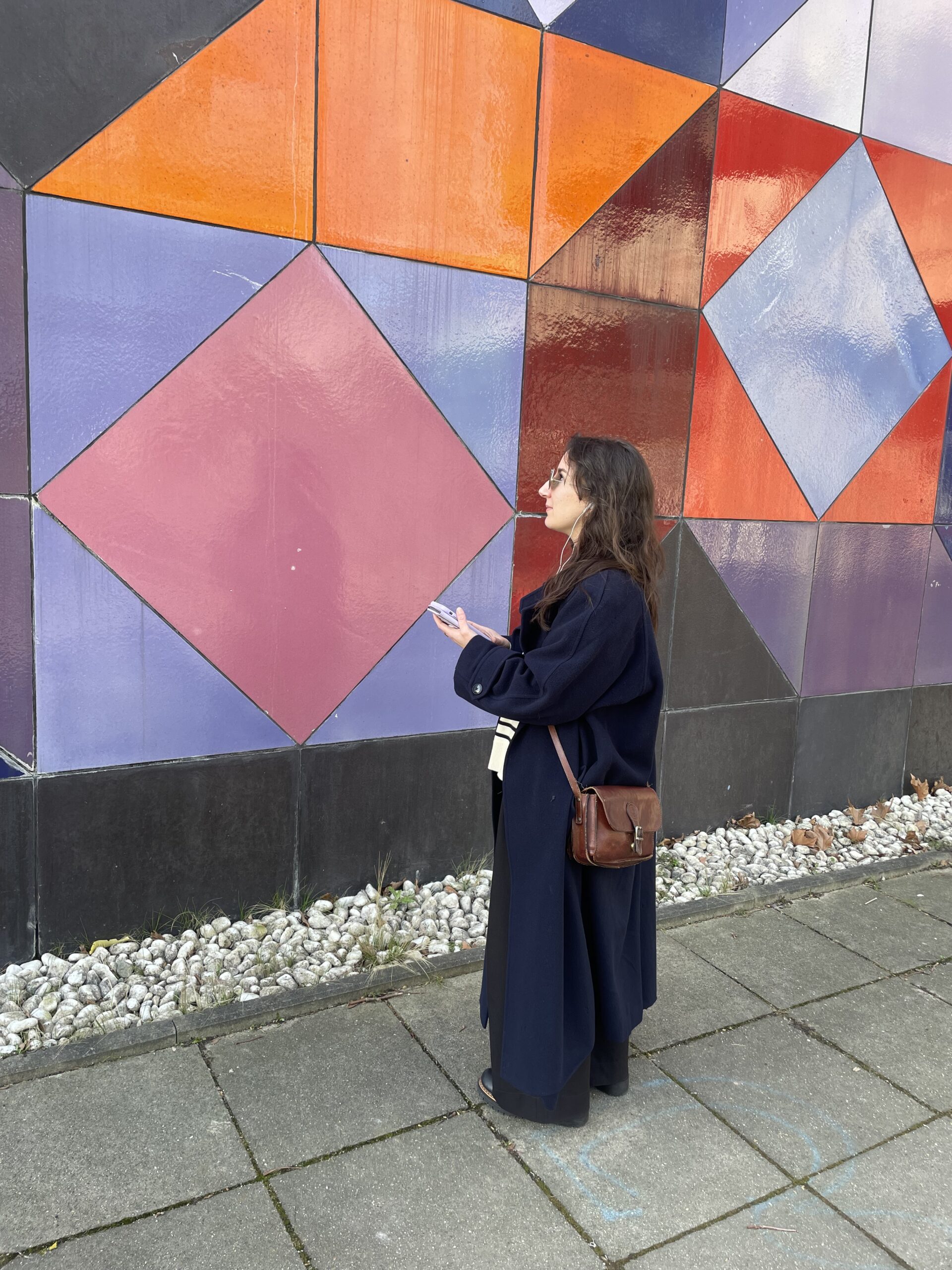 Frau steht mit Smartphone vor Keramikwand "Ohne Titel" von Victor Vasarely am HZO der RUB.