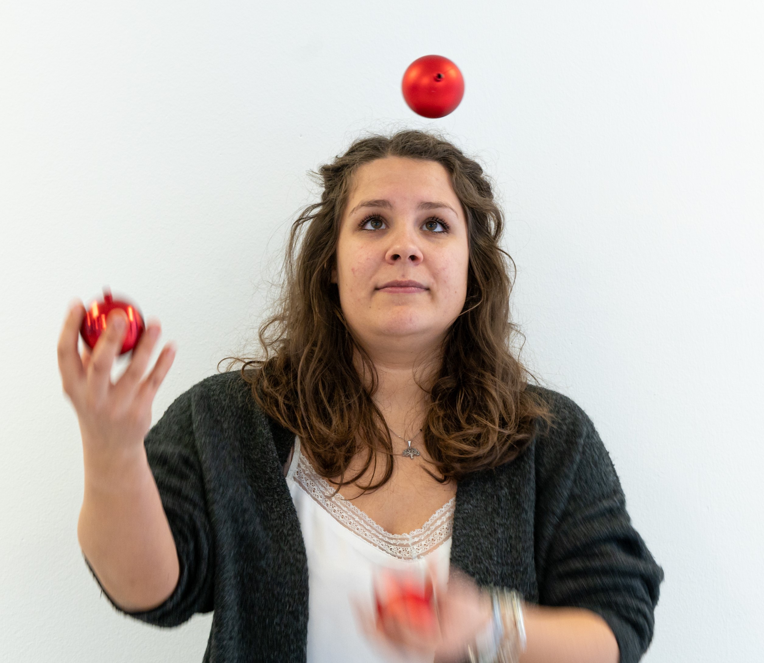Frau jongliert mit drei roten Weihnachtskugeln.