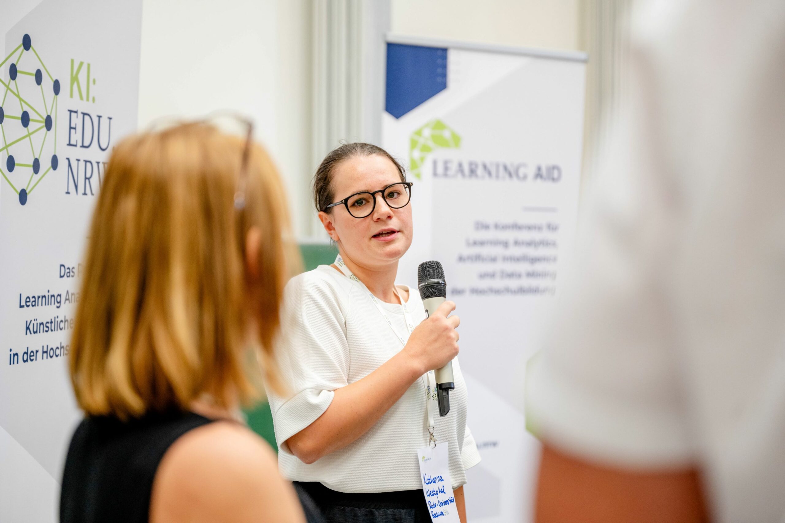 Studentische Mitarbeiterin des eTeam Digitalisierung hält Mikrofon in der Hand und spricht zur Learning AID.