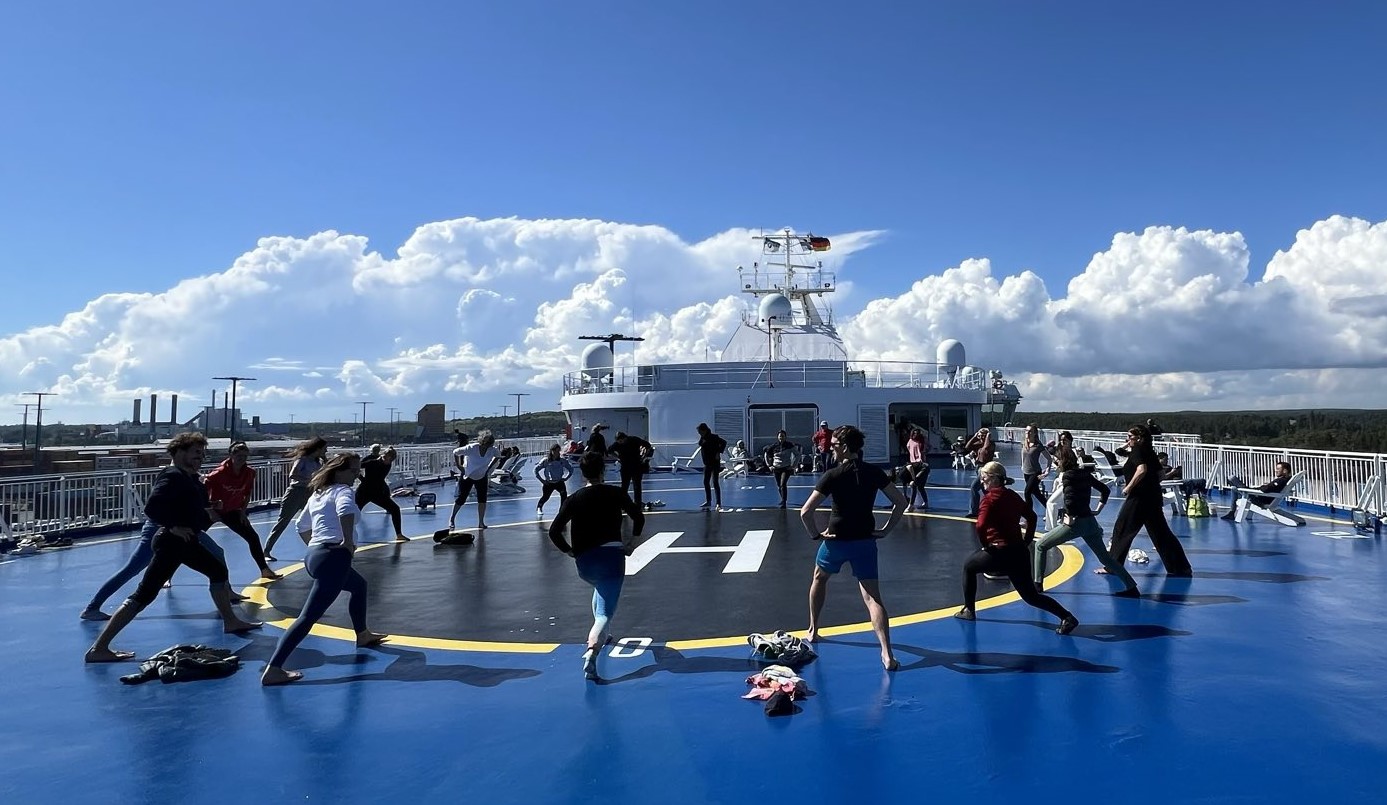 Gruppe von Menschen bildet einen Kreis auf dem Schiffsdeck und macht Sportübungen.